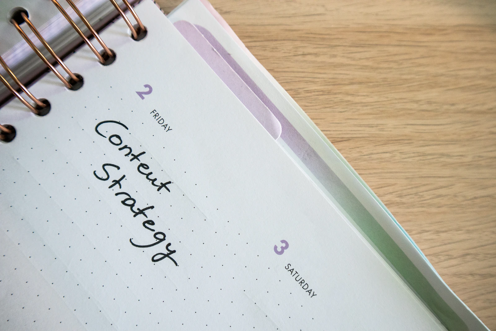 Spiral-bound planner with Content Strategy handwritten on a dotted page.